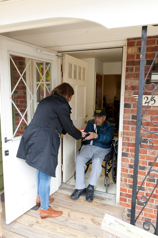 A volunteer delivering a meal to a client at their front door