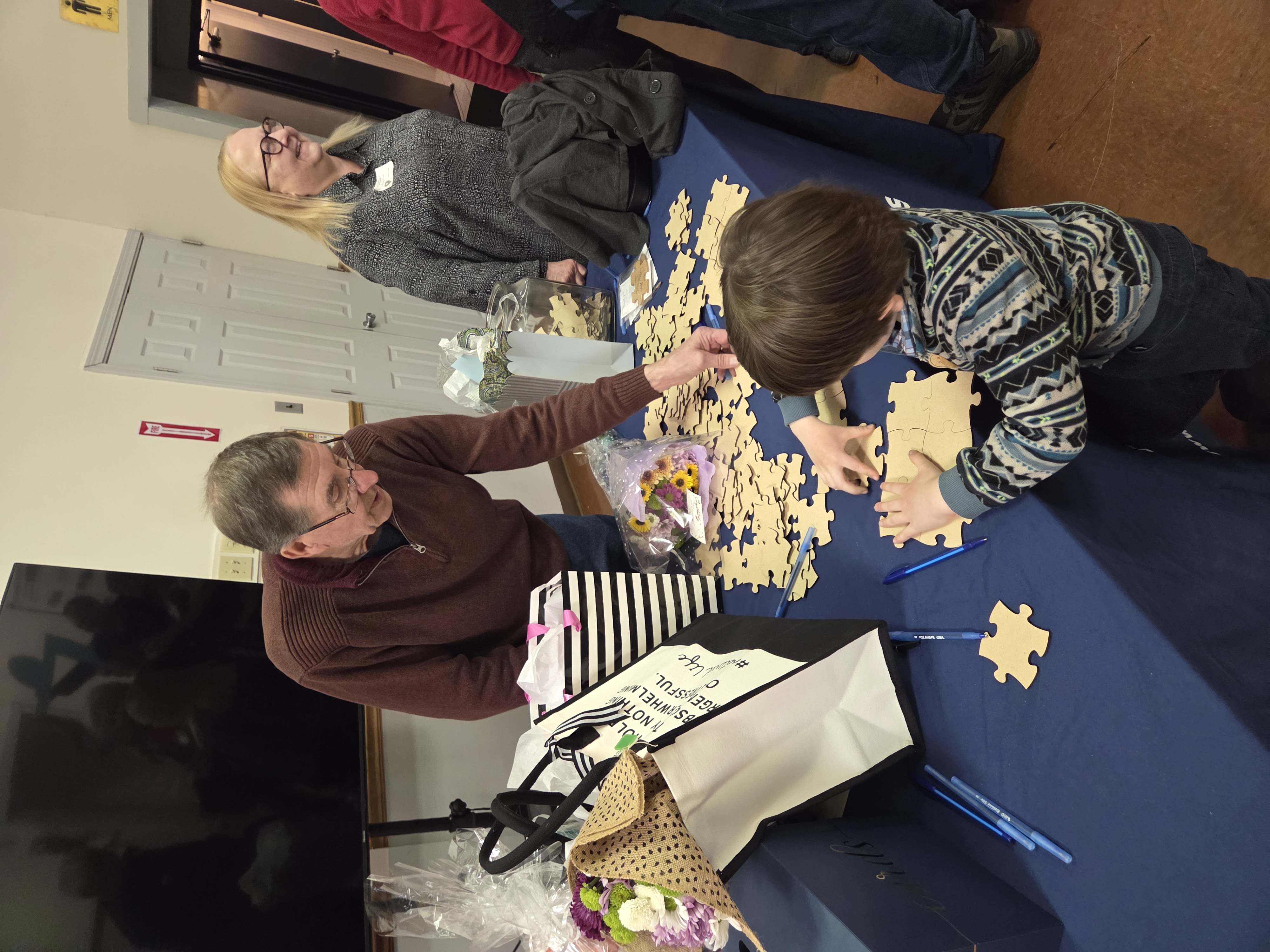 A volunteer and young child working on a puzzle together at a Meals on Wheels community event