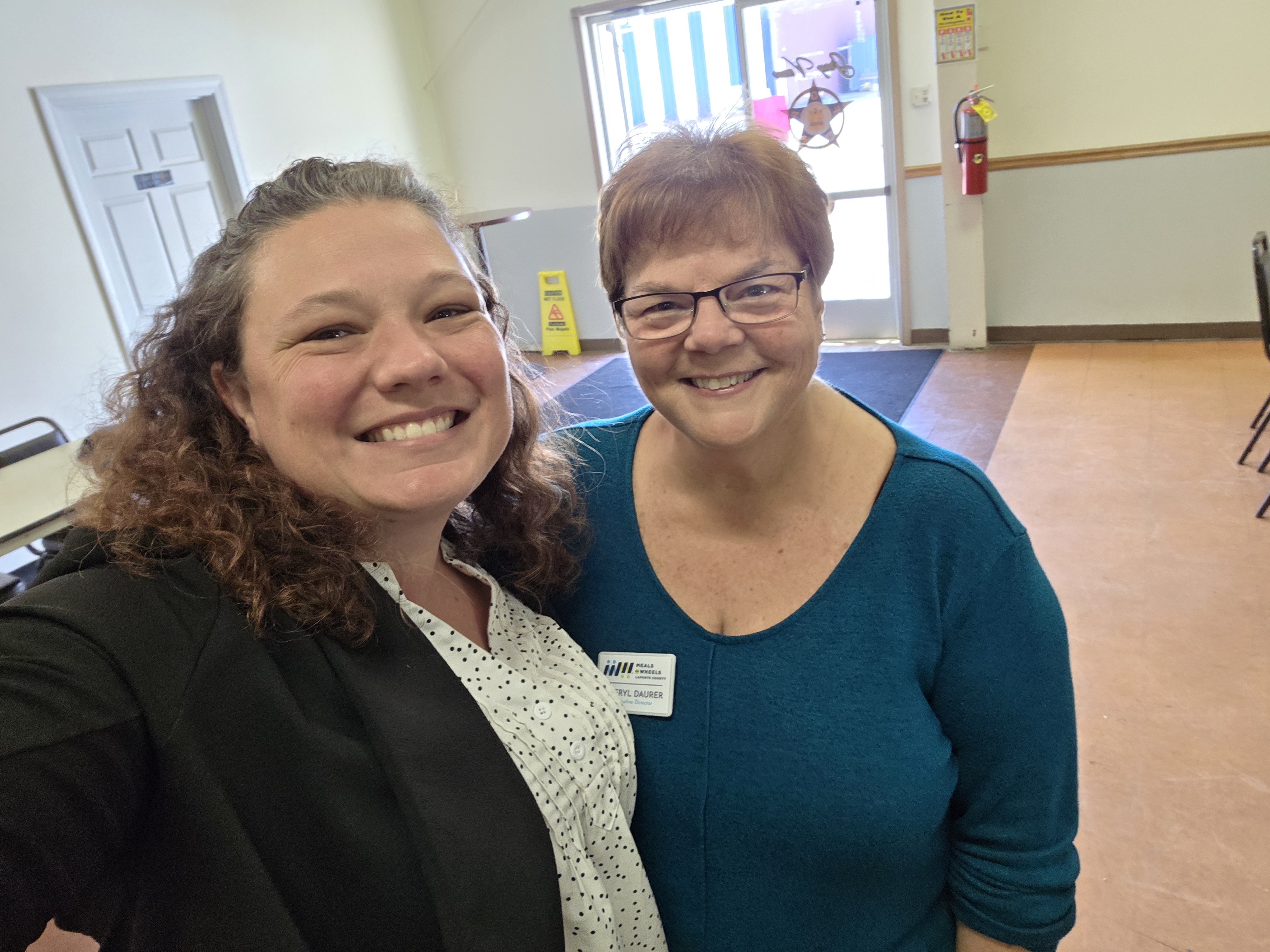 Two Meals on Wheels staff members smiling at a community outreach event