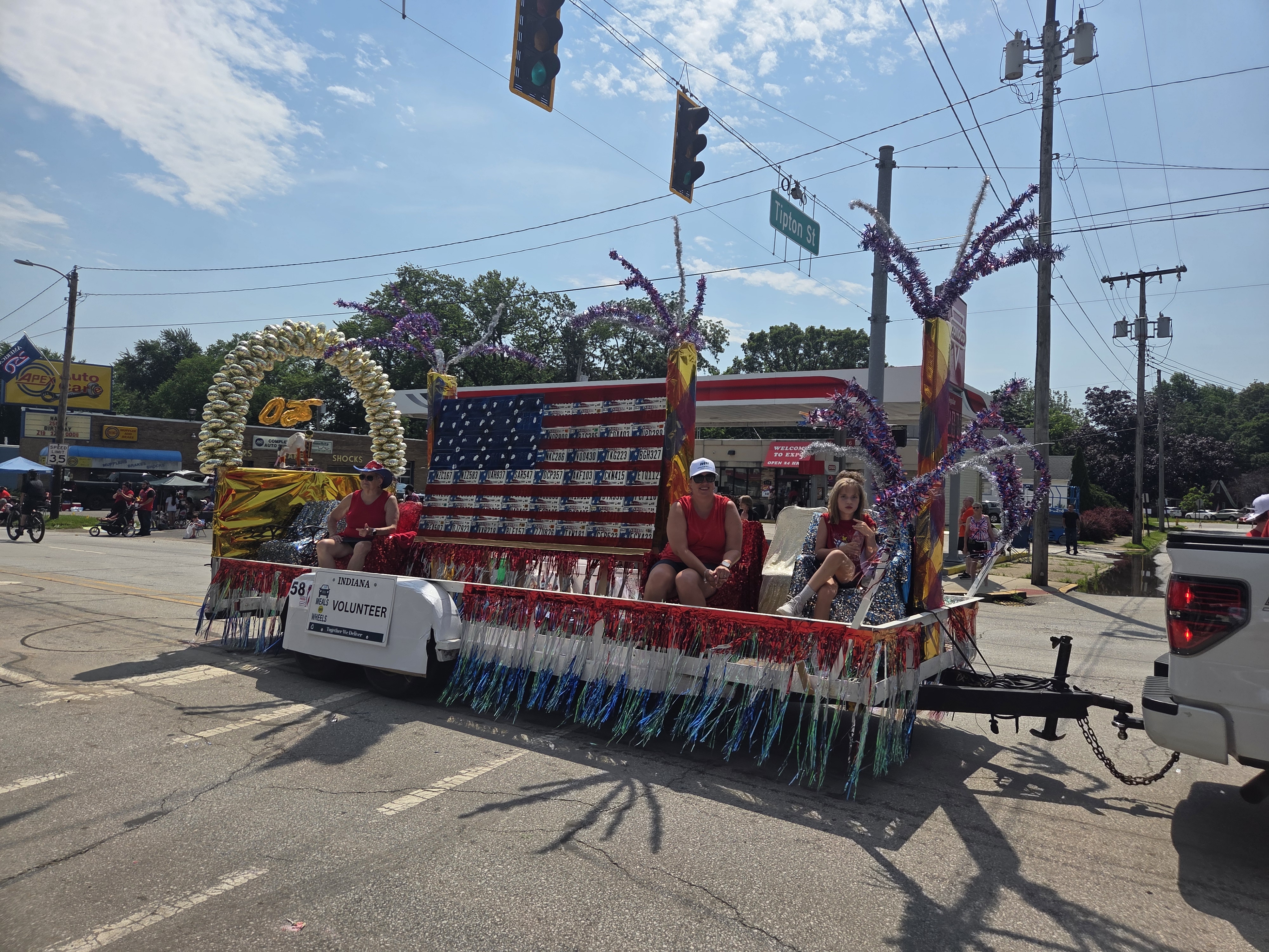 Volunteers riding the Meals on Wheels parade float and waving to the crowd