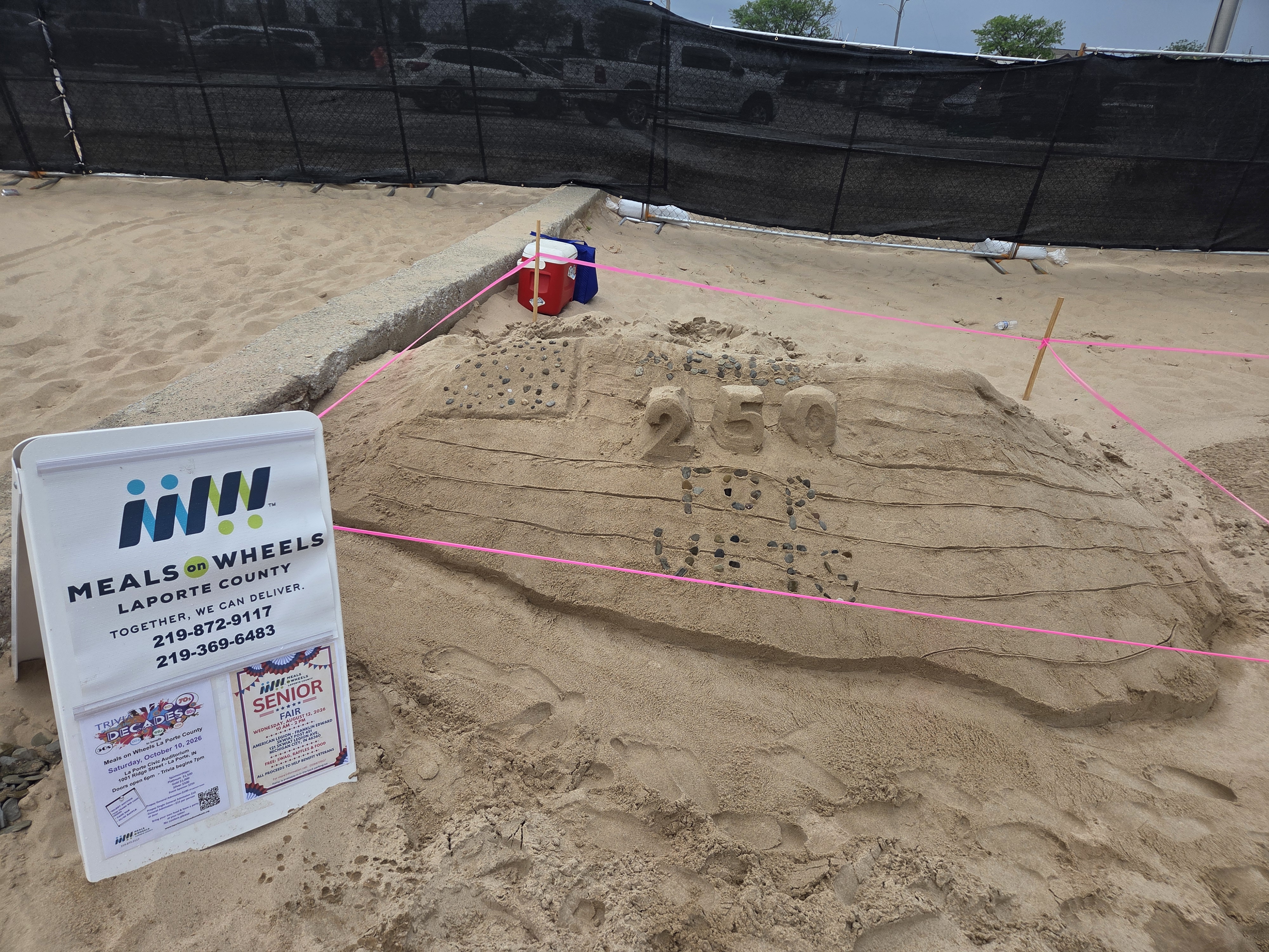 Team member carefully sculpting details in the Meals on Wheels sand sculpture entry