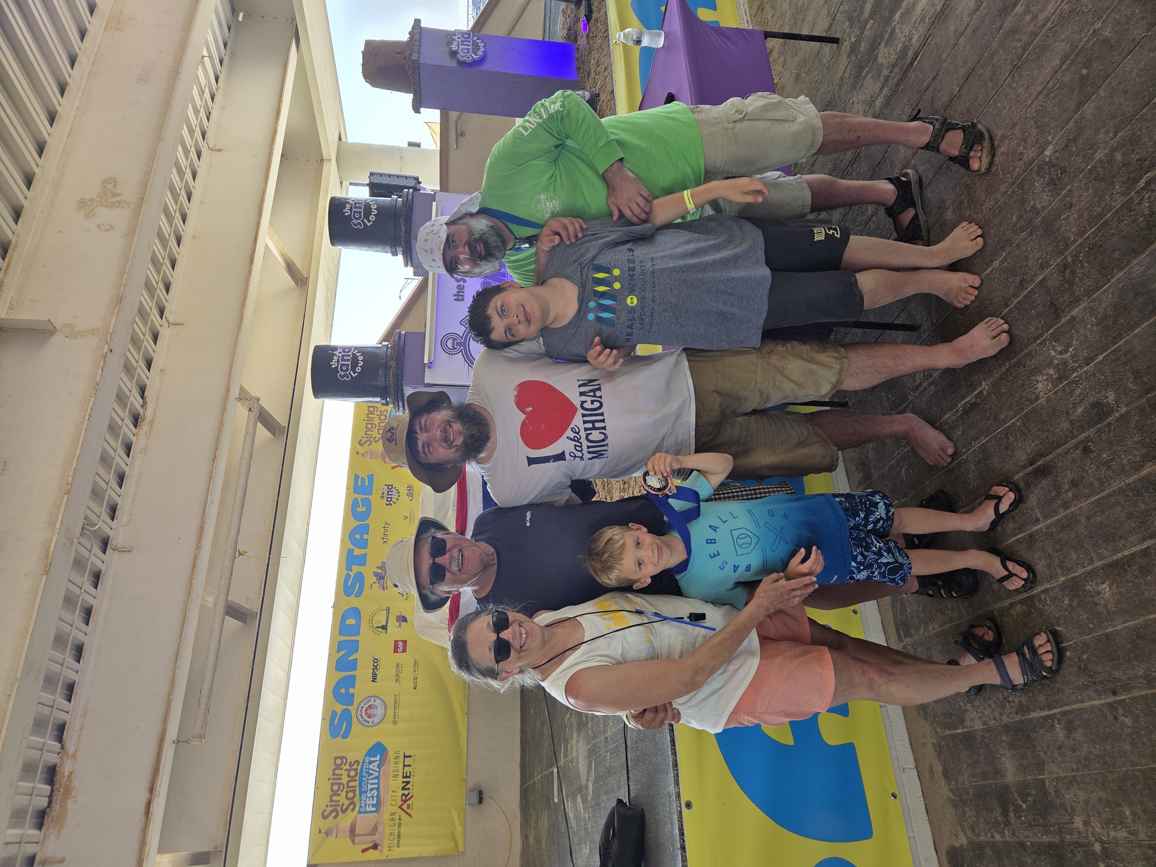 The Meals on Wheels team gathered together at the Sand Sculpture Festival stage