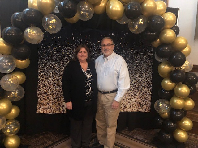 A couple posing under a balloon arch at a Meals on Wheels fundraising gala