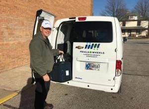 A volunteer loading meals from a Meals on Wheels delivery van