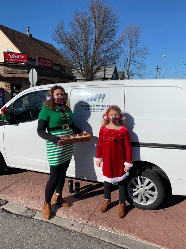 Holiday meal delivery volunteers in festive costumes by the Meals on Wheels van