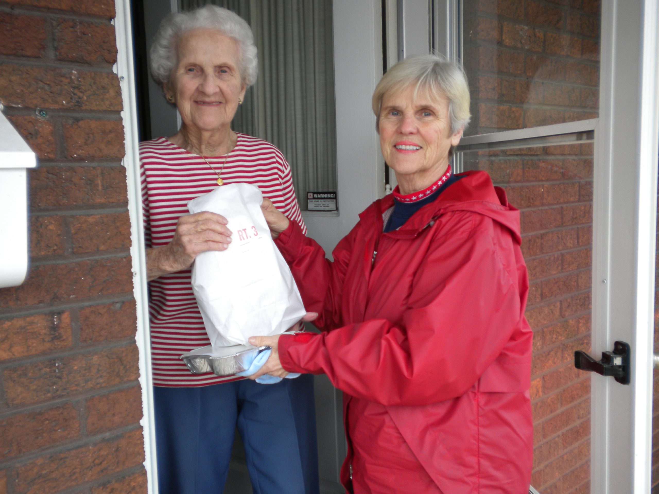 A Meals on Wheels volunteer delivering a meal at a client's doorstep