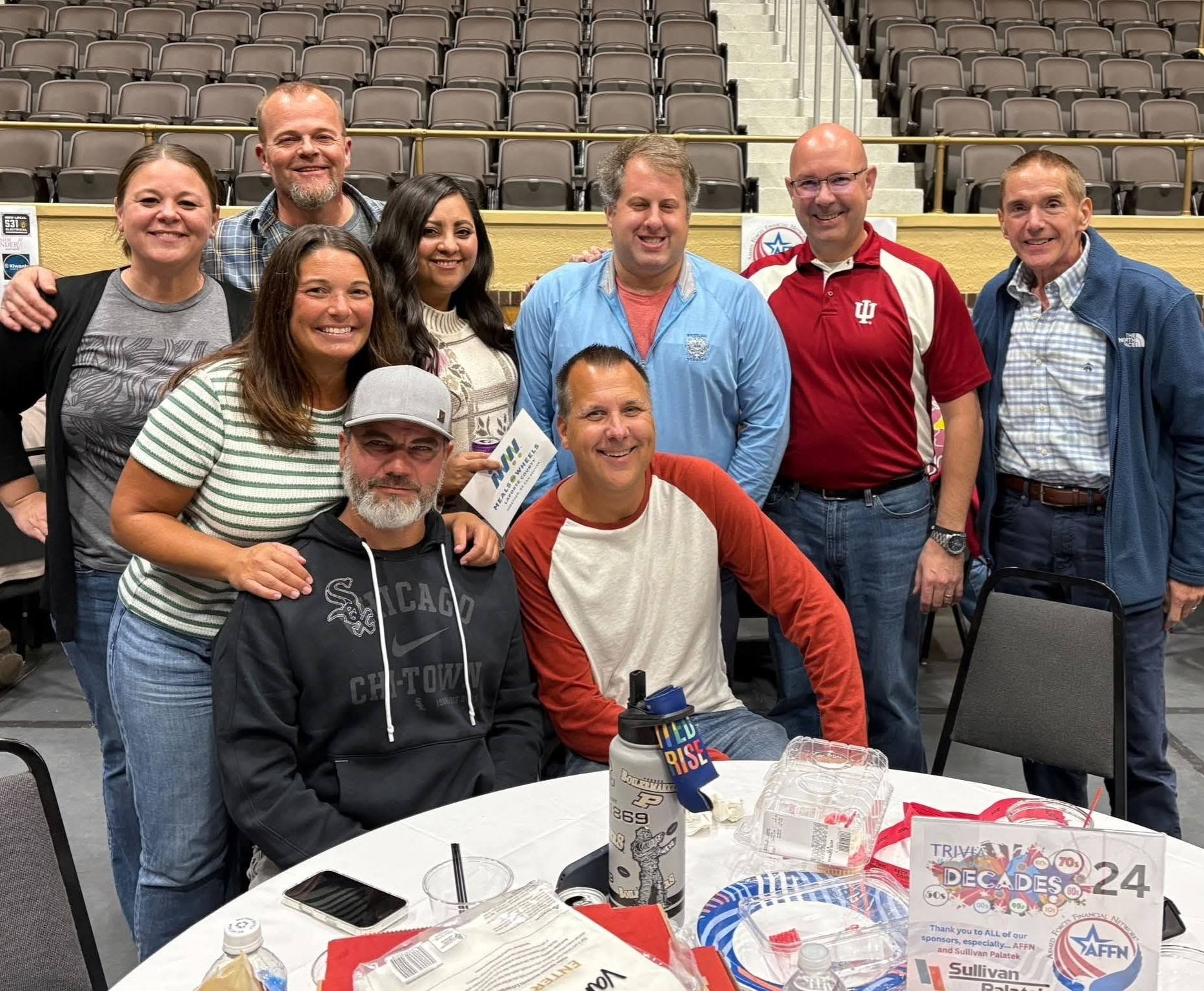 Team posing together at their table with sponsor signage